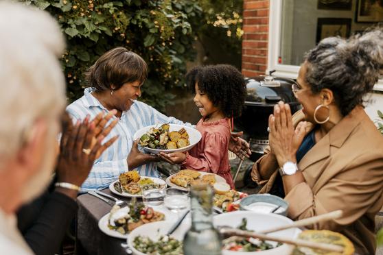 A family surrounding a table of plant based foods